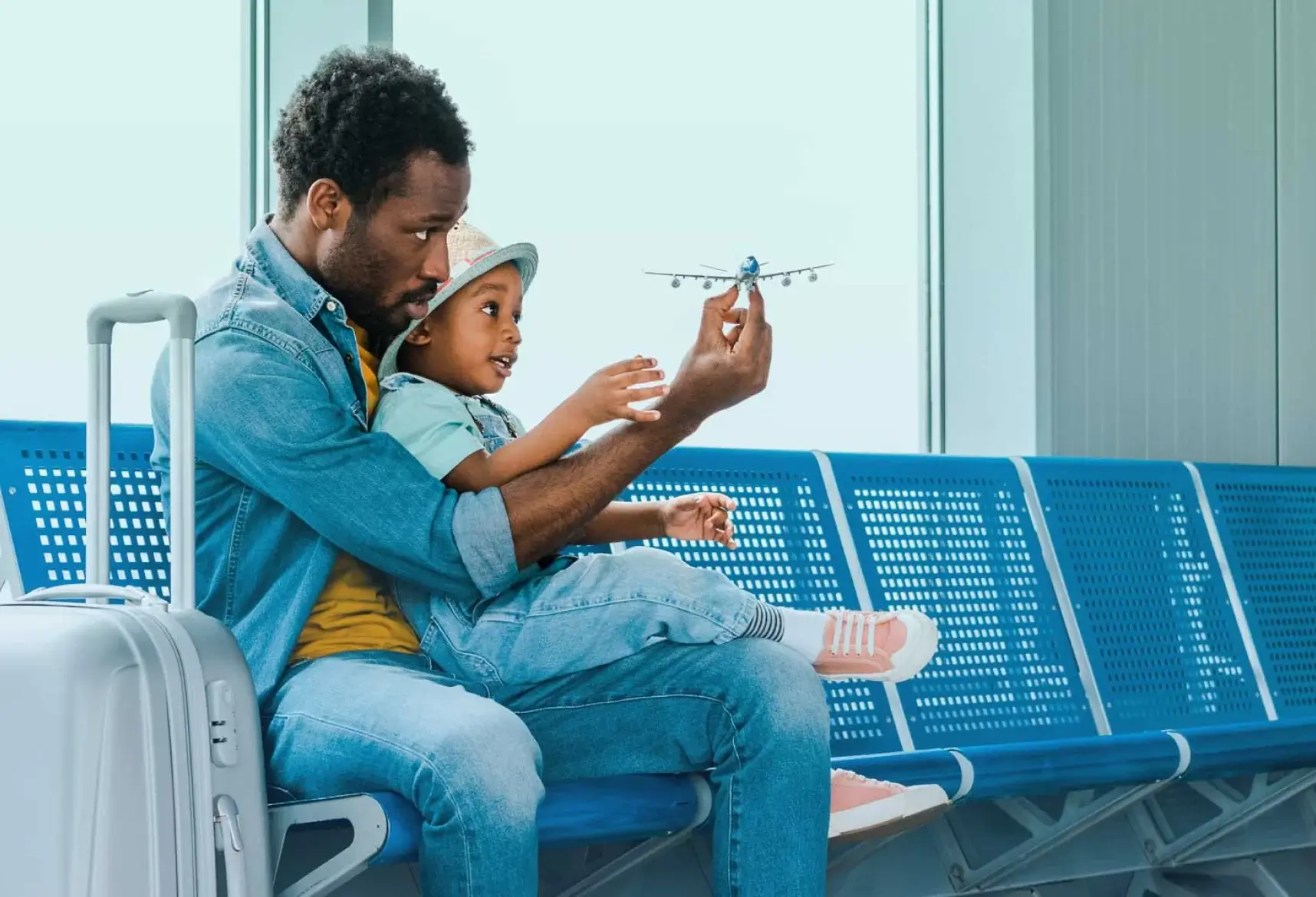 Father with son waiting at the airport playing with a toy plane