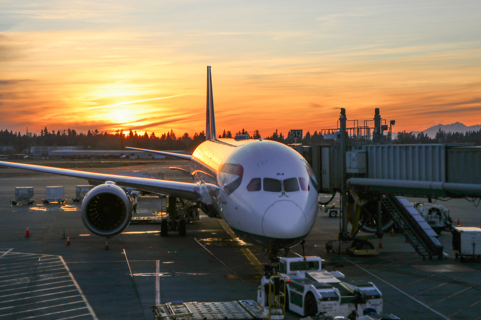 A British Airways Boeing 787 parked at a gate with the sun setting in the background at Seattle-Tacoma International Airport - Seattle, Washington, USA - veovo slot coordination